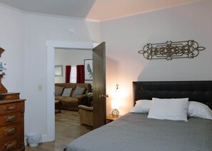 Een slaapkamer met een bed, een dressoir, een stoel en een deur naar een andere kamer.