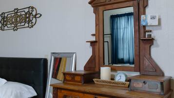 A wooden dresser with drawers and a mirror, a bed with a headboard, and a wall-mounted decorative piece.