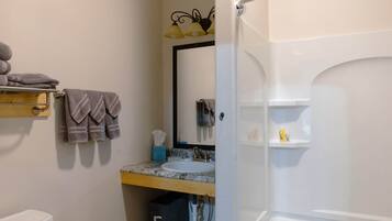 A bathroom with a toilet, sink, towel rack, and shower.