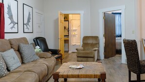 Una sala de estar con un sofá de cuero marrón, una mesa de centro de madera y dos sillones.