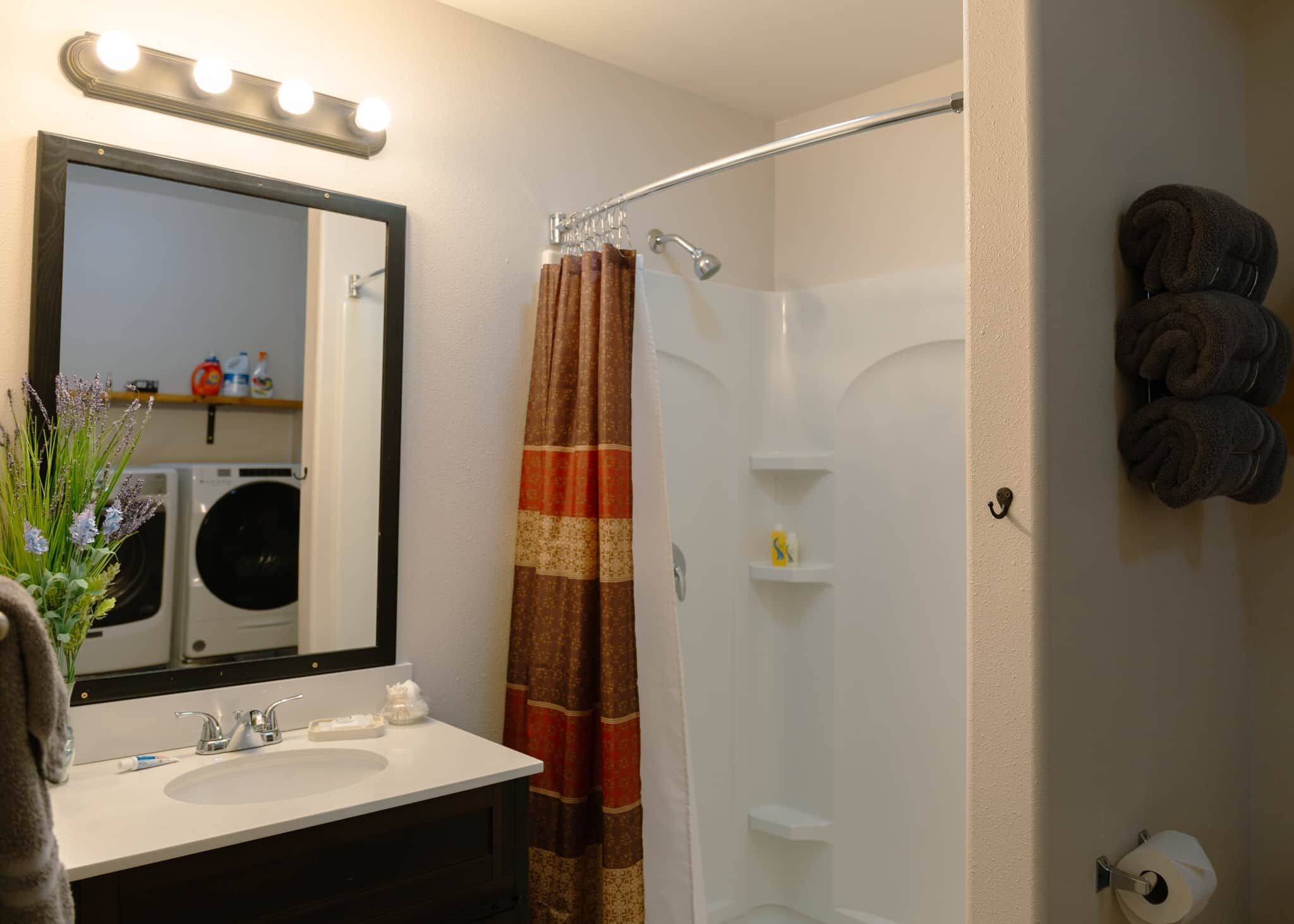 Un baño con lavabo, espejo y cortina de ducha.