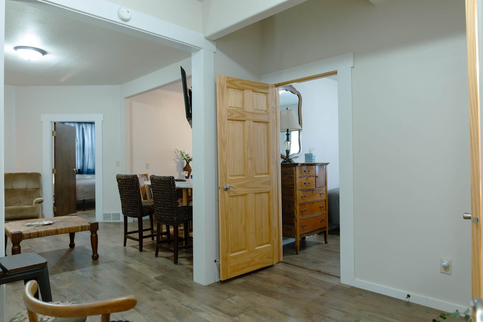 Une pièce comprenant une table à manger, des chaises, un buffet en bois et une porte donnant sur une autre pièce.