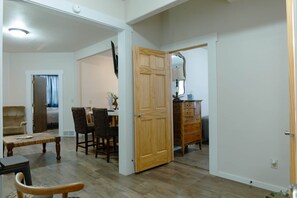 A room with a dining table, chairs, a wooden cabinet, and a door leading to another room. - East Lodge – Spacious 3BR Stay in Mobridge (Mobridge)