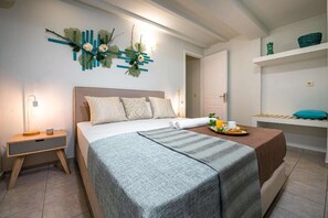 A modern bedroom with a bed, bedside table, and a decorative wall piece. - Tortuga  Pelouzo island view I (Vasilikos)