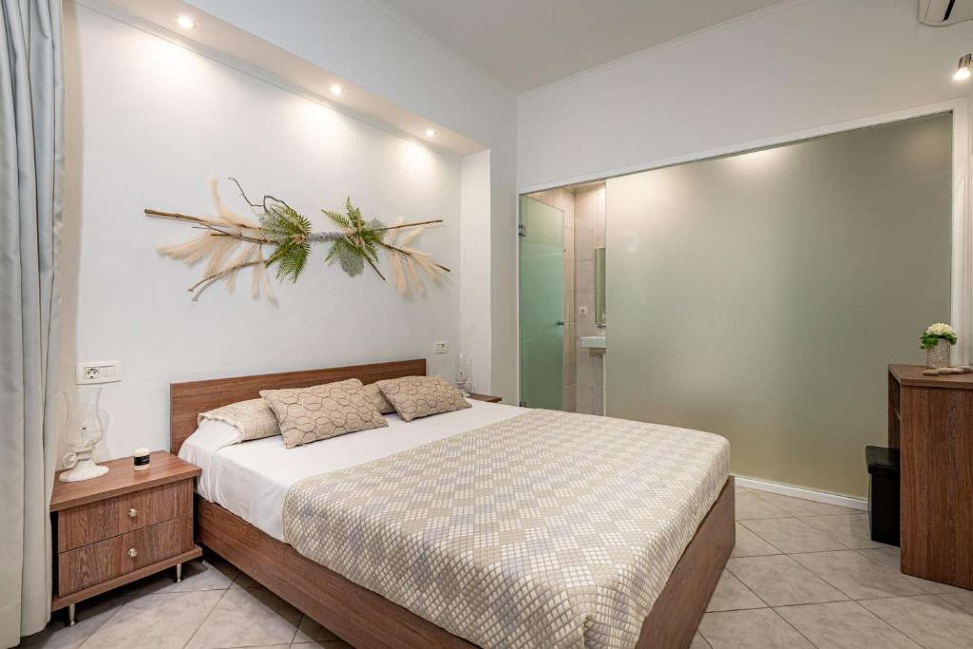 A bedroom with a bed, nightstand, and a wall-mounted plant.