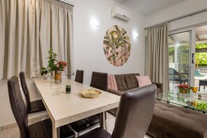 Spiseområde med bord, stole, en sofa og udsigt til det fri.