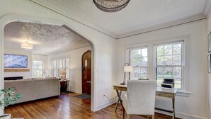 Ein großzügiger Wohnraum mit Holzdielen, einem großen Sofa, einer Essecke mit Tisch und Stühlen sowie einem an der Wand befestigten Fernseher.
