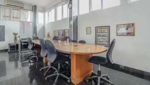 Una sala de conferencias con una amplia mesa ovalada, sillas de oficina negras y una pizarra.