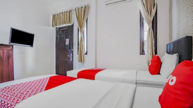 Una habitación de hotel con dos camas, un televisor y un armario.