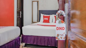 Una habitación de hotel con dos camas, un armario de madera y una puerta con el cartel de no molestar.