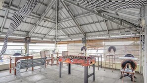 Un espacio al aire libre cubierto con mesa de fútbol, bancos y sillas.