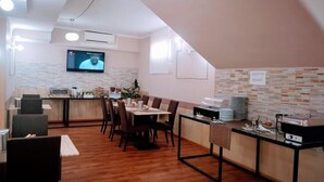 Un'area pranzo moderna con un tavolo lungo, sedie, un bancone con un televisore e un muro con motivo decorativo.
