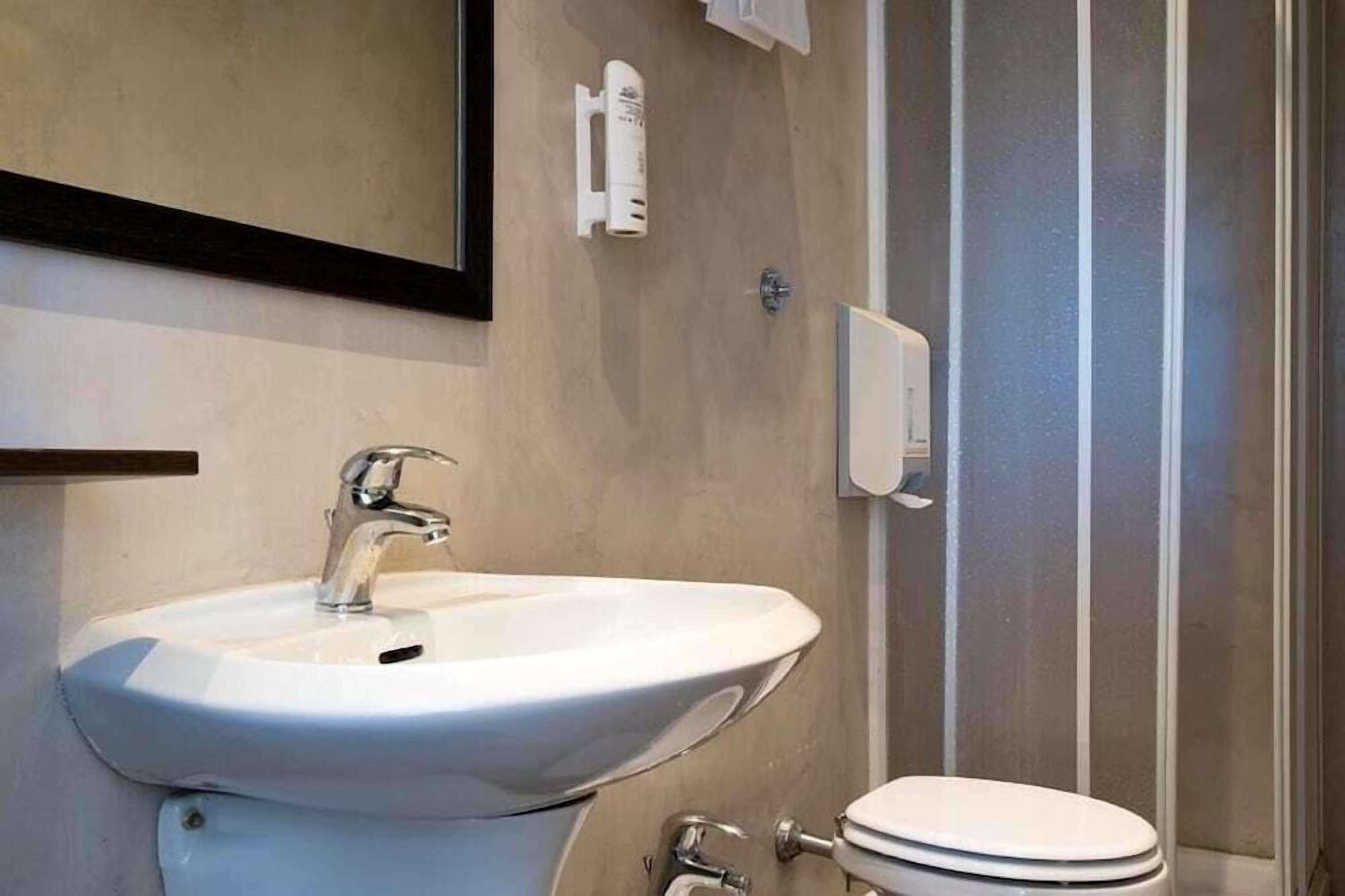 A bathroom with a white sink, a toilet, and a mirror.