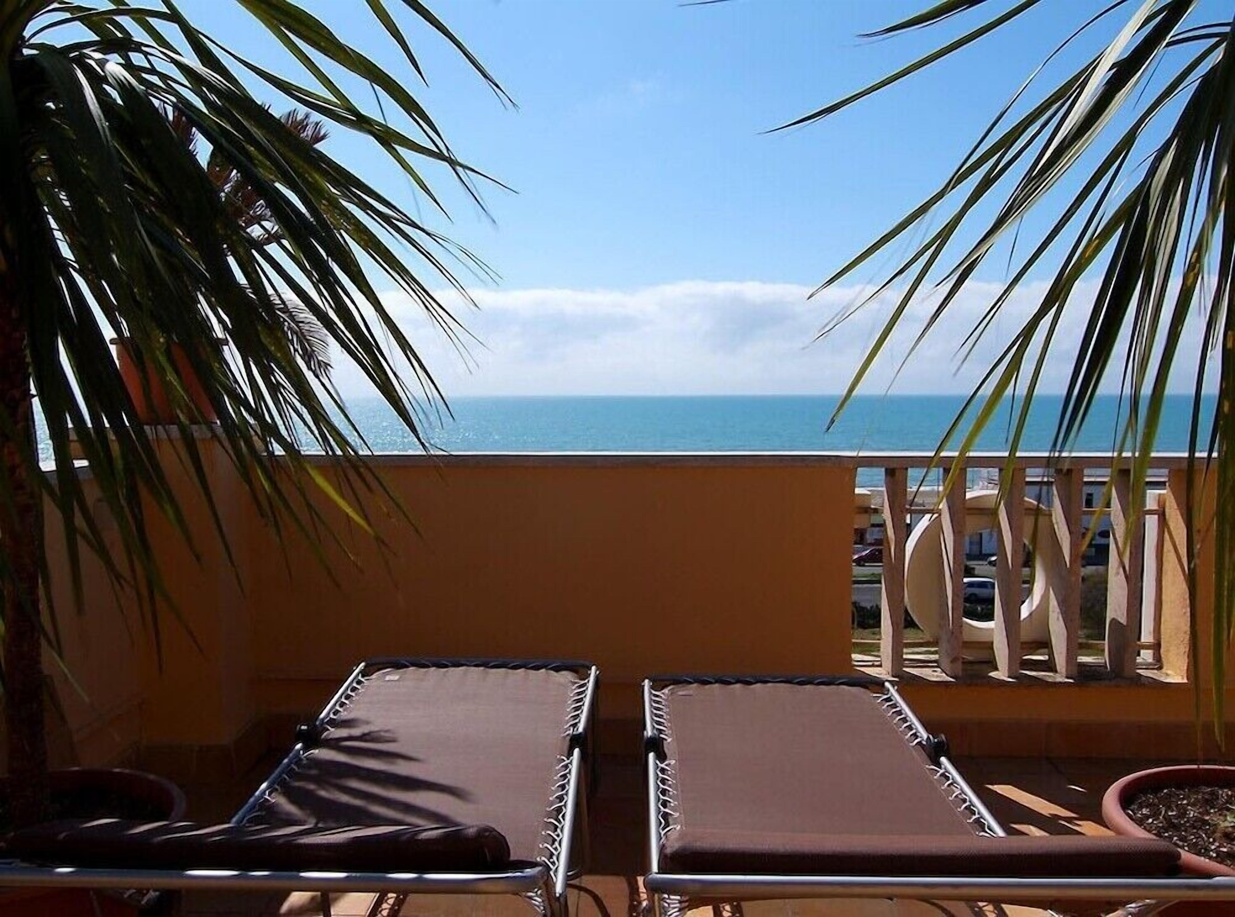 A balcony with two sun loungers facing a clear view of the ocean.