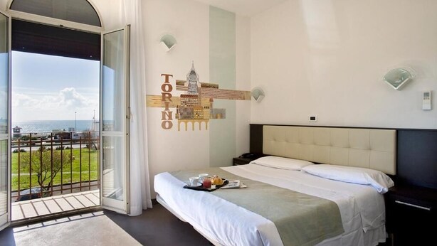 Una camera d'albergo con un letto, vista sulla città e un balcone.