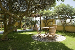 An outdoor patio area with a wooden table and chairs, surrounded by lush greenery and trees. - Hotel La Riva (Rome)