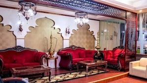 A luxurious room with red sofas, a wooden coffee table, and ornate wall decorations. - Phoenix Hotel Deira (Dubai)