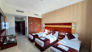 A hotel room with two beds, a wooden wardrobe, a desk with a telephone, and a mirror. - Phoenix Hotel Deira (Dubai)