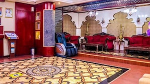 A lobby with a patterned carpet, red sofas, a reception desk, and decorative wall panels. - Phoenix Hotel Deira (Dubai)