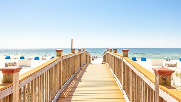 A wooden boardwalk leading to a beach with beach chairs and umbrellas. - Breathtaking Panoramic Views of the Gulf (Pensacola)