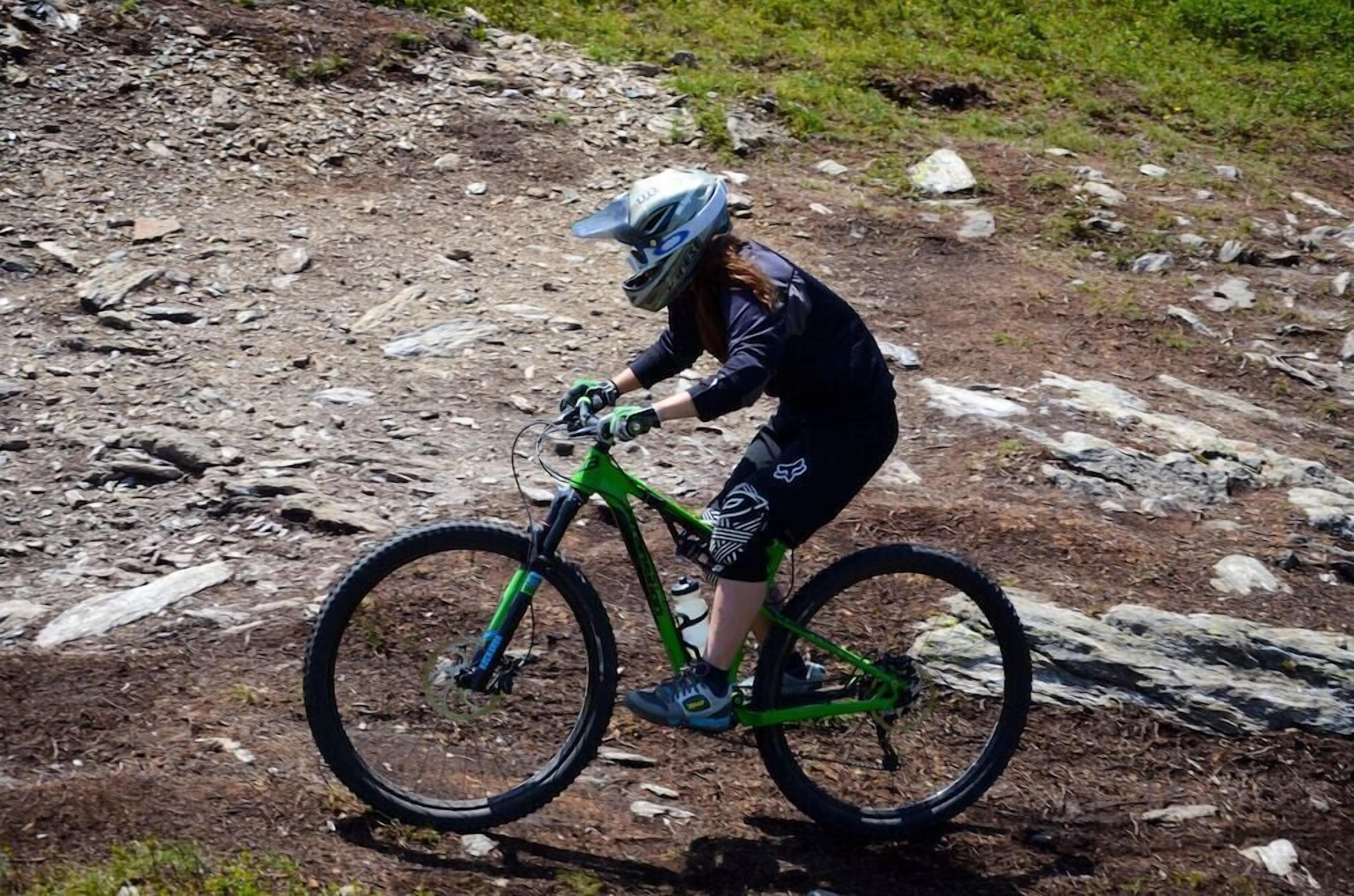 A person riding a green mountain bike on a rocky trail.