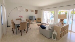 Ein geräumiger Wohnbereich mit Esstisch, Sofa und Fernseher.
