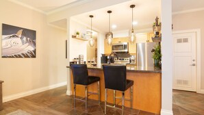 A modern kitchen with a bar area, stainless steel appliances, and pendant lighting. - Sprawling Corner Condo, Amazing 1st floor deck, Ski in/out, Sleeps 4 (Whistler)