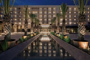 A hotel with a reflective pool, palm trees, and a modern building facade. - The Landmark Nicosia, Autograph Collection (Nicosia)