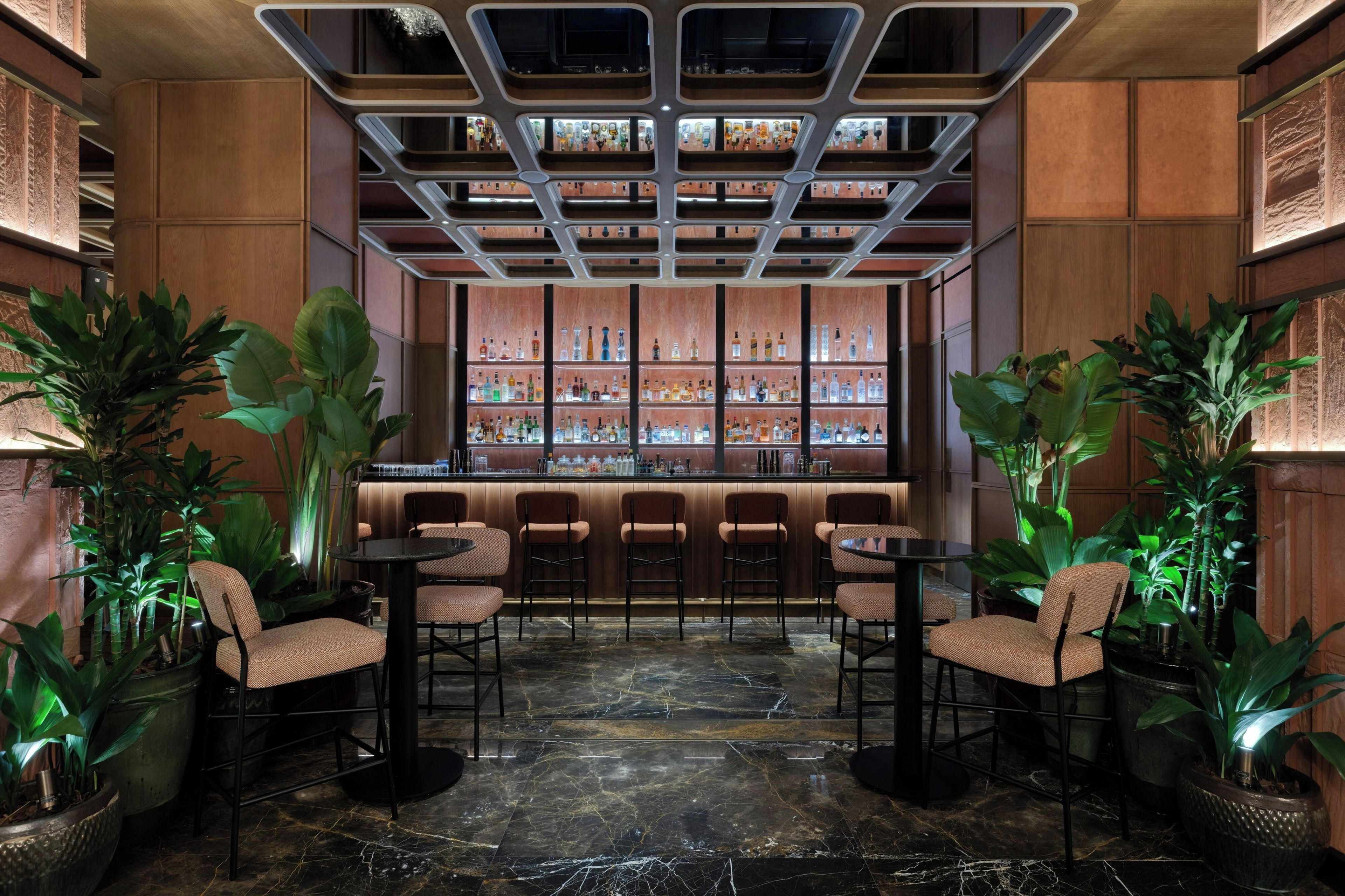 A bar area with a marble floor, wooden paneling, and a variety of bottles on shelves.