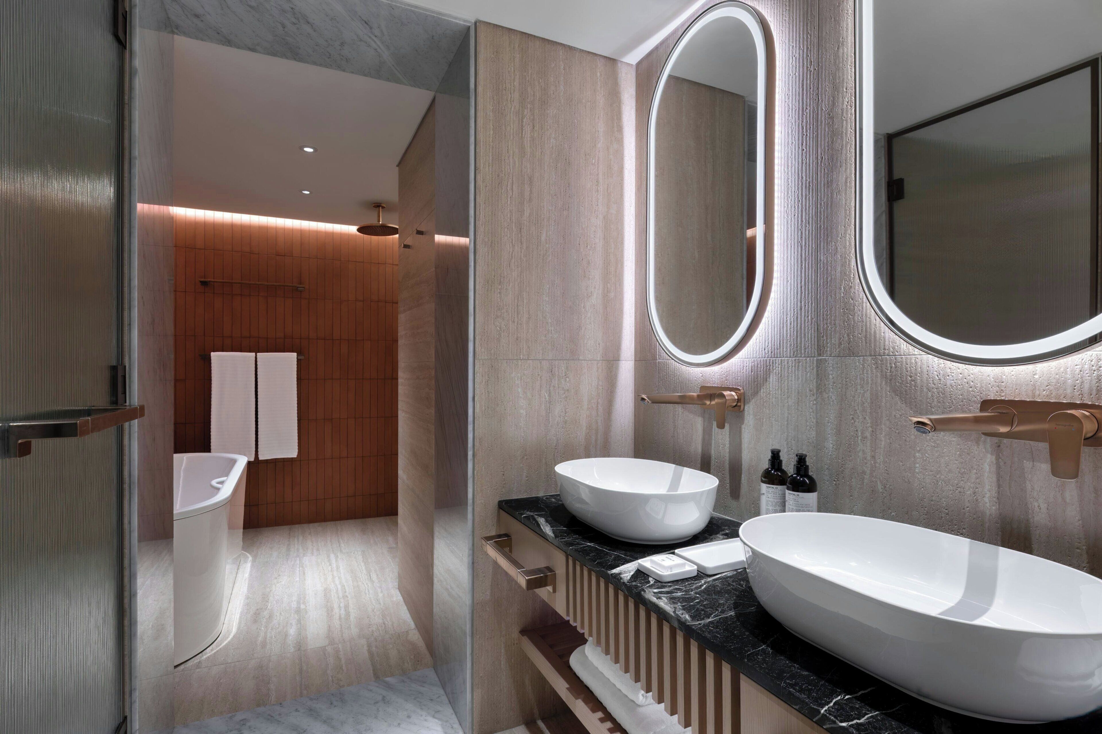 Un baño moderno con un lavamanos ovalado grande, un espejo y un perchero para toallas.