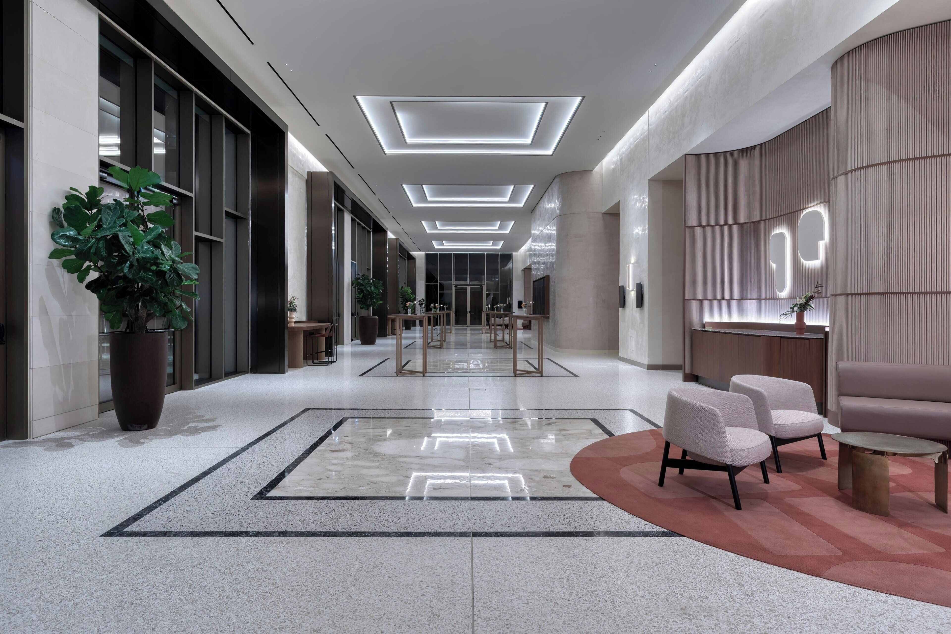 A modern lobby with a long corridor, seating area, and a reception desk.