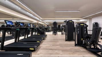Un gimnasio con cintas de correr, máquinas de pesas y equipo de ejercicio.