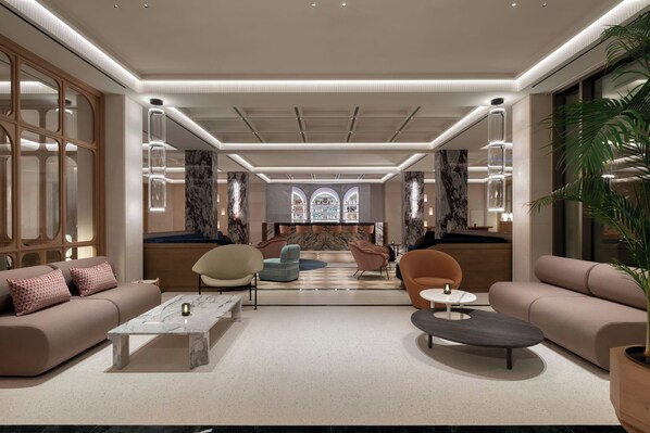 Un vestíbulo de hotel moderno con una zona de estar central, un ventanal grande y una pared decorativa.