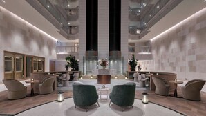 A modern lobby with seating areas, a central decorative piece, and a high ceiling with balconies. - The Landmark Nicosia, Autograph Collection (Nicosia)