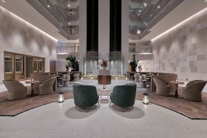 En moderne lobby med siddeområder, et centralt dekorativt element og et højtloftet rum med altaner.