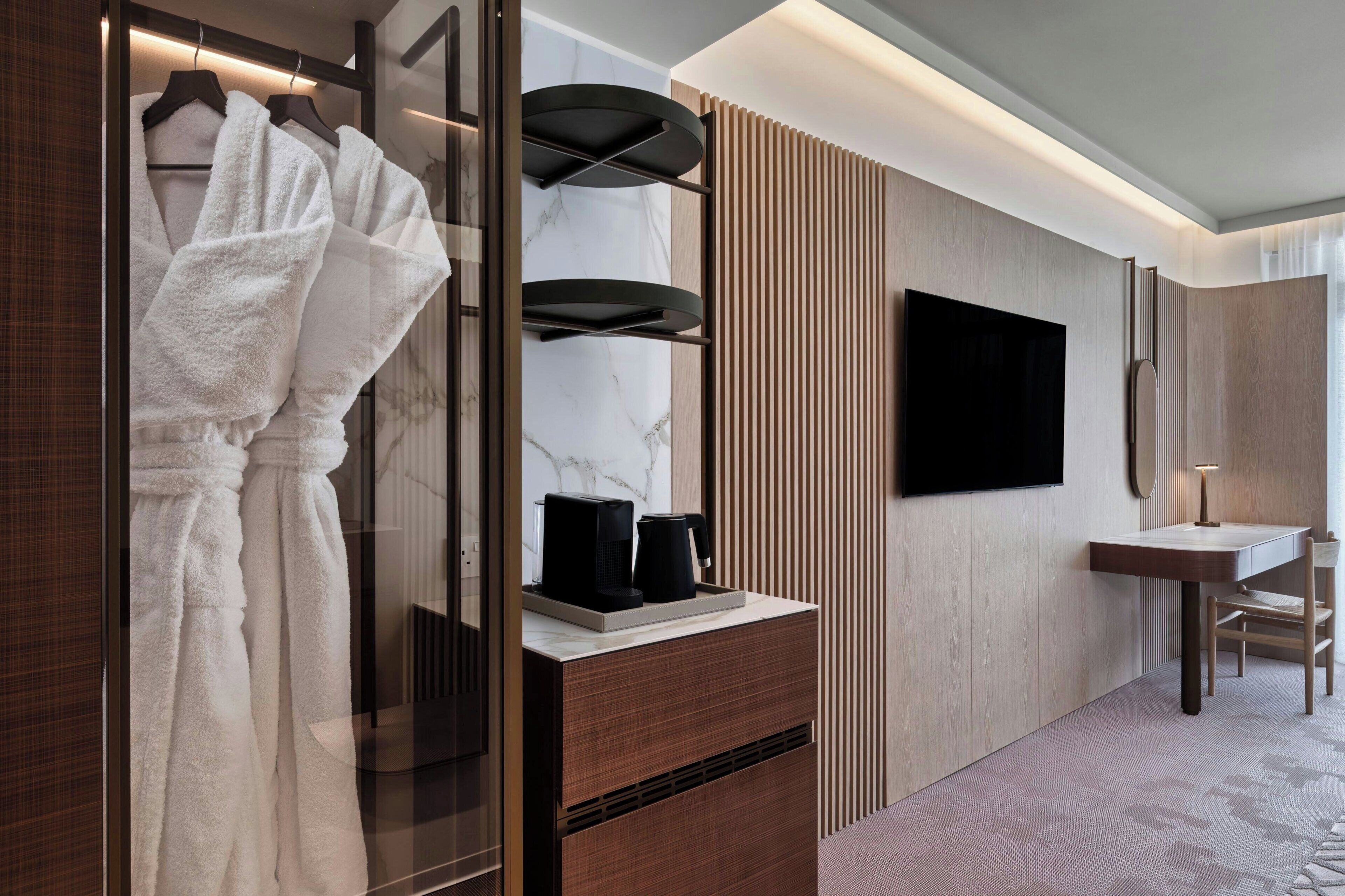 Un baño moderno con tocador, espejo, toallero y televisor.