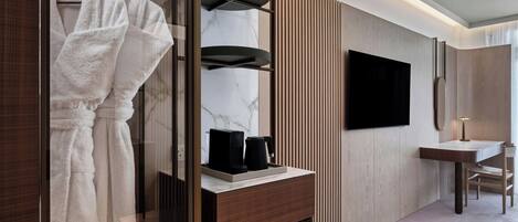 Un baño moderno con tocador, espejo, toallero y televisor.