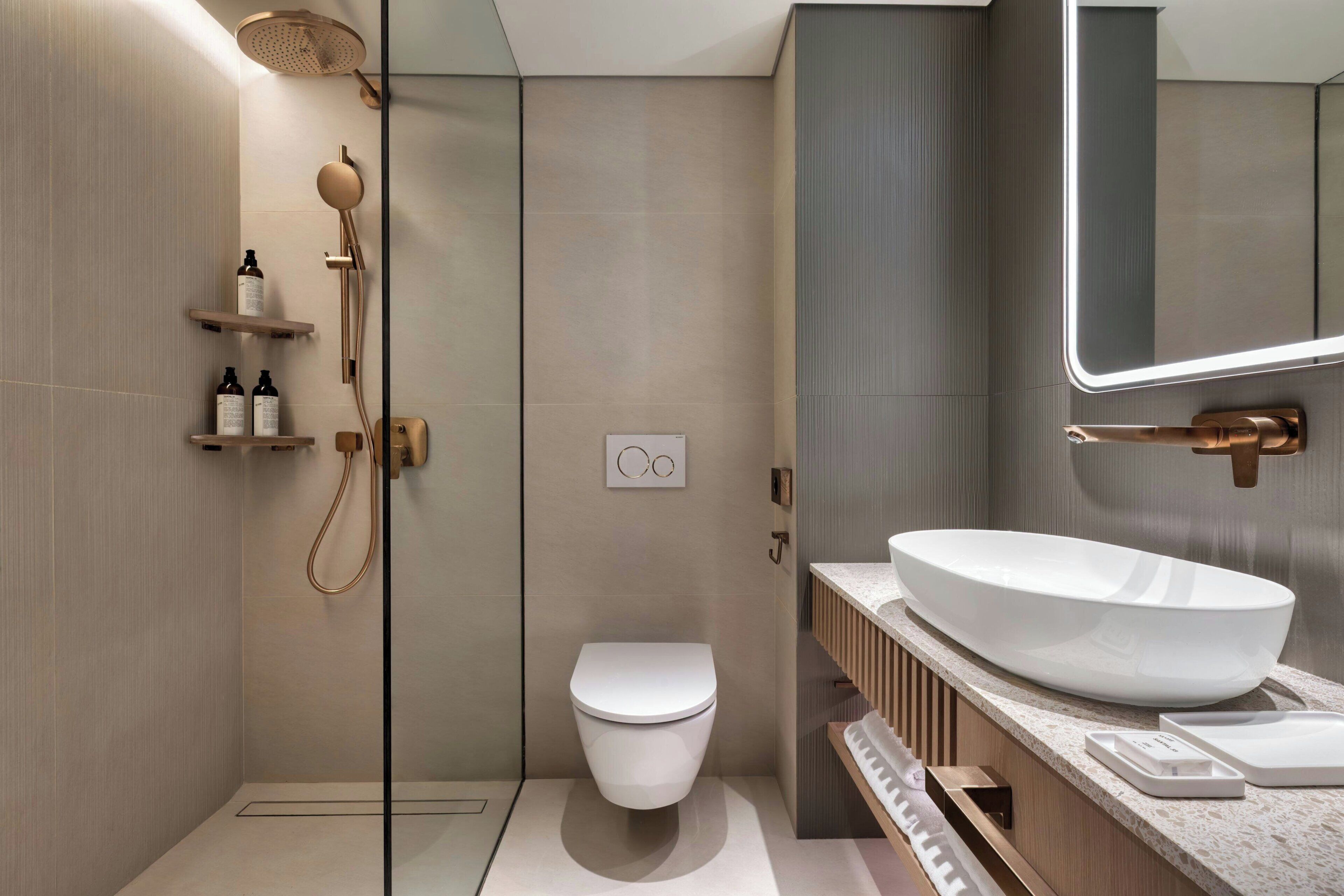 A modern bathroom with a shower, toilet, and vanity with a large sink.
