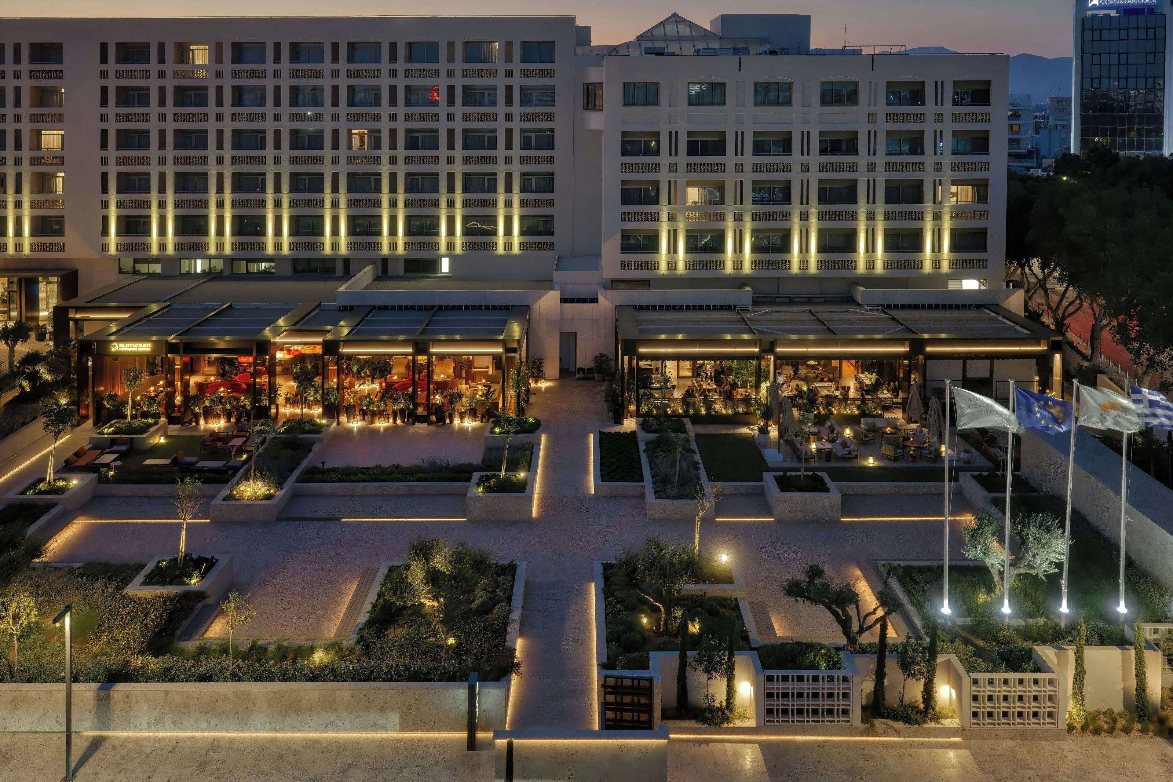 Un hotel con varios pisos, zonas de estar al aire libre y un patio bien iluminado.