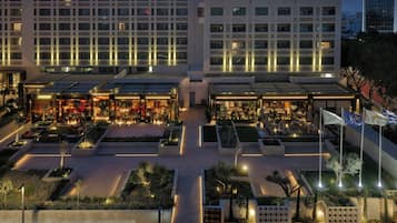 Un hotel con varios pisos, zonas de estar al aire libre y un patio bien iluminado.