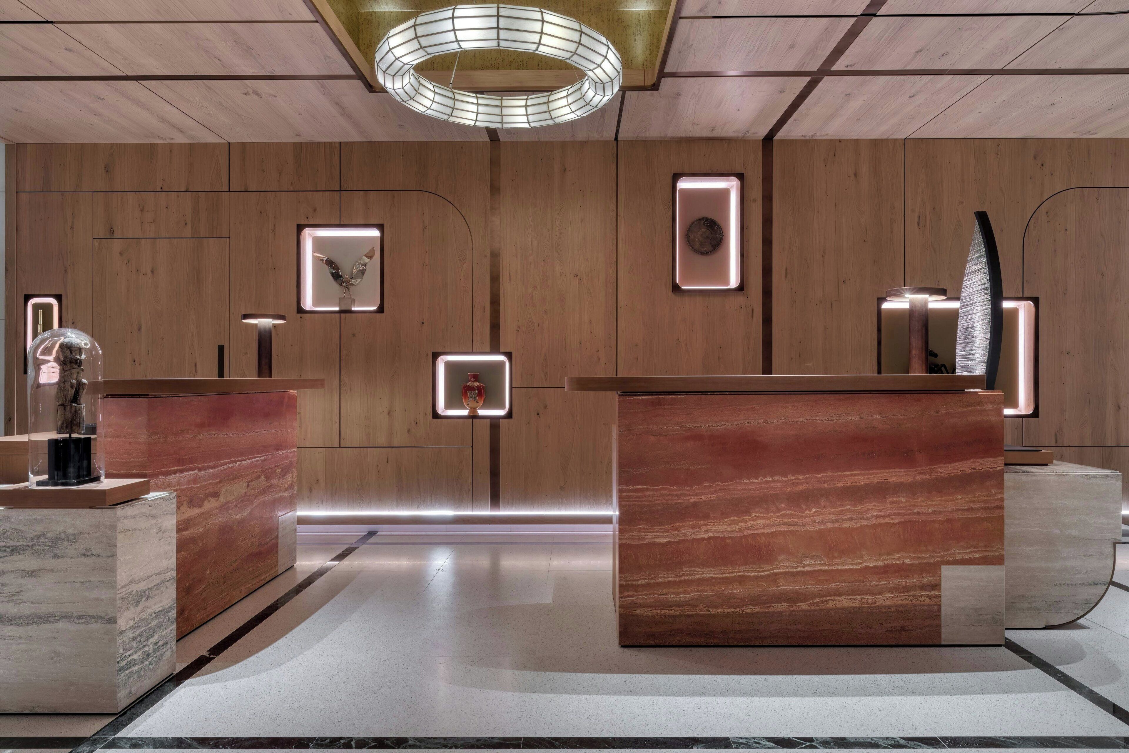A reception area with wooden panel walls, marble counters, and modern lighting fixtures.