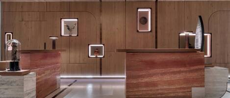 A reception area with wooden panel walls, marble counters, and modern lighting fixtures.
