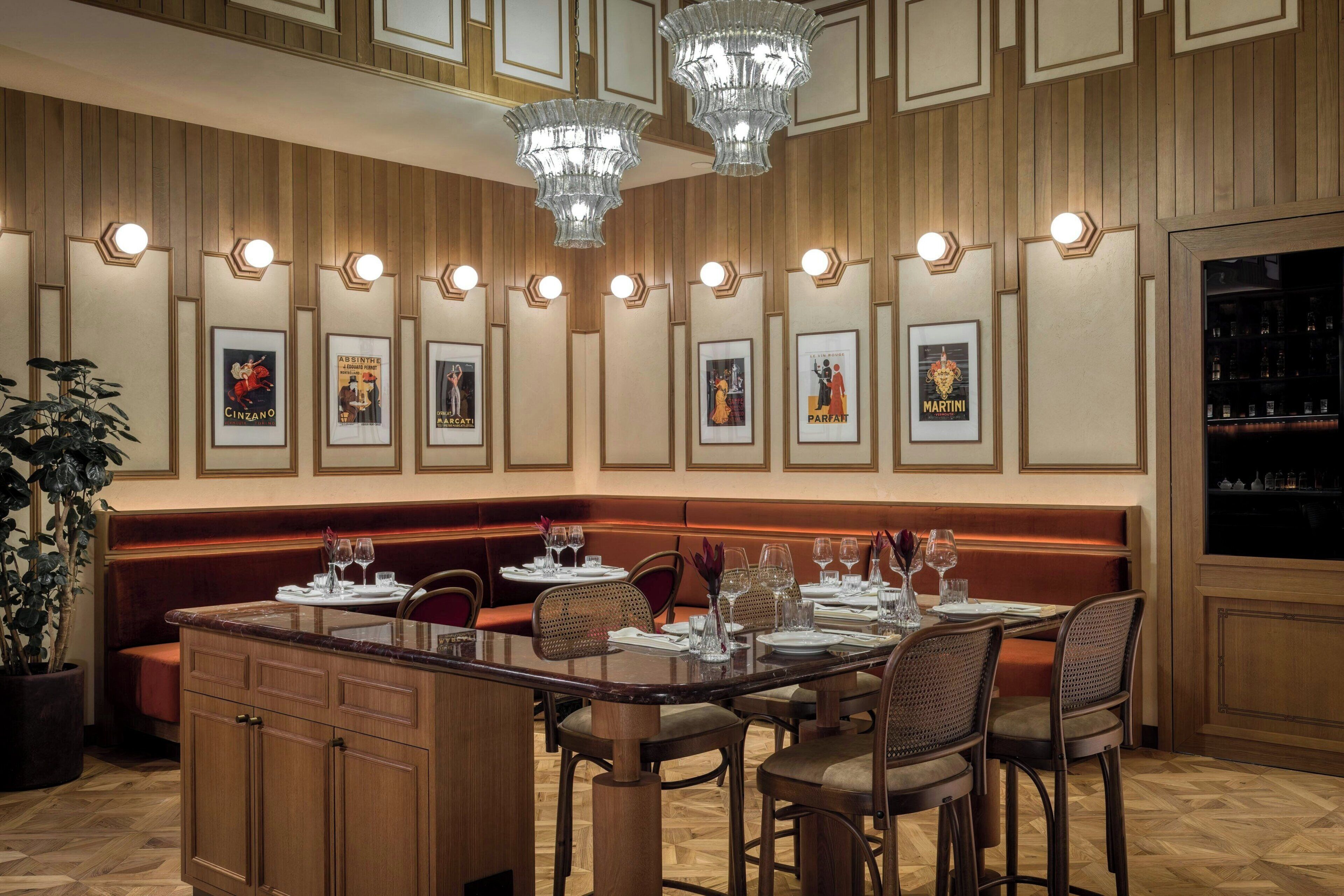 Un restaurant avec un long banc en bois, un îlot central doté de sièges et des tableaux encadrés accrochés au mur.