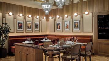 Un restaurant avec un long banc en bois, un îlot central doté de sièges et des tableaux encadrés accrochés au mur.