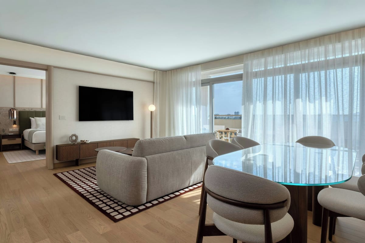 Et moderne hotelværelse med sofa, et glasbord og et fladskærms-tv.