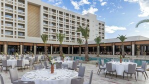 A hotel with outdoor dining areas, a swimming pool, and a large building with multiple balconies. - The Landmark Nicosia, Autograph Collection (Nicosia)