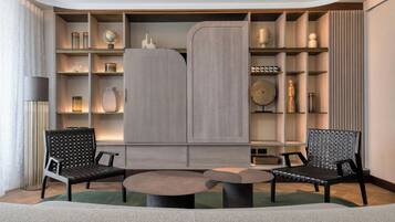 Una sala de estar moderna con dos sillas negras, una mesa redonda y una estantería empotrada con varios objetos decorativos.