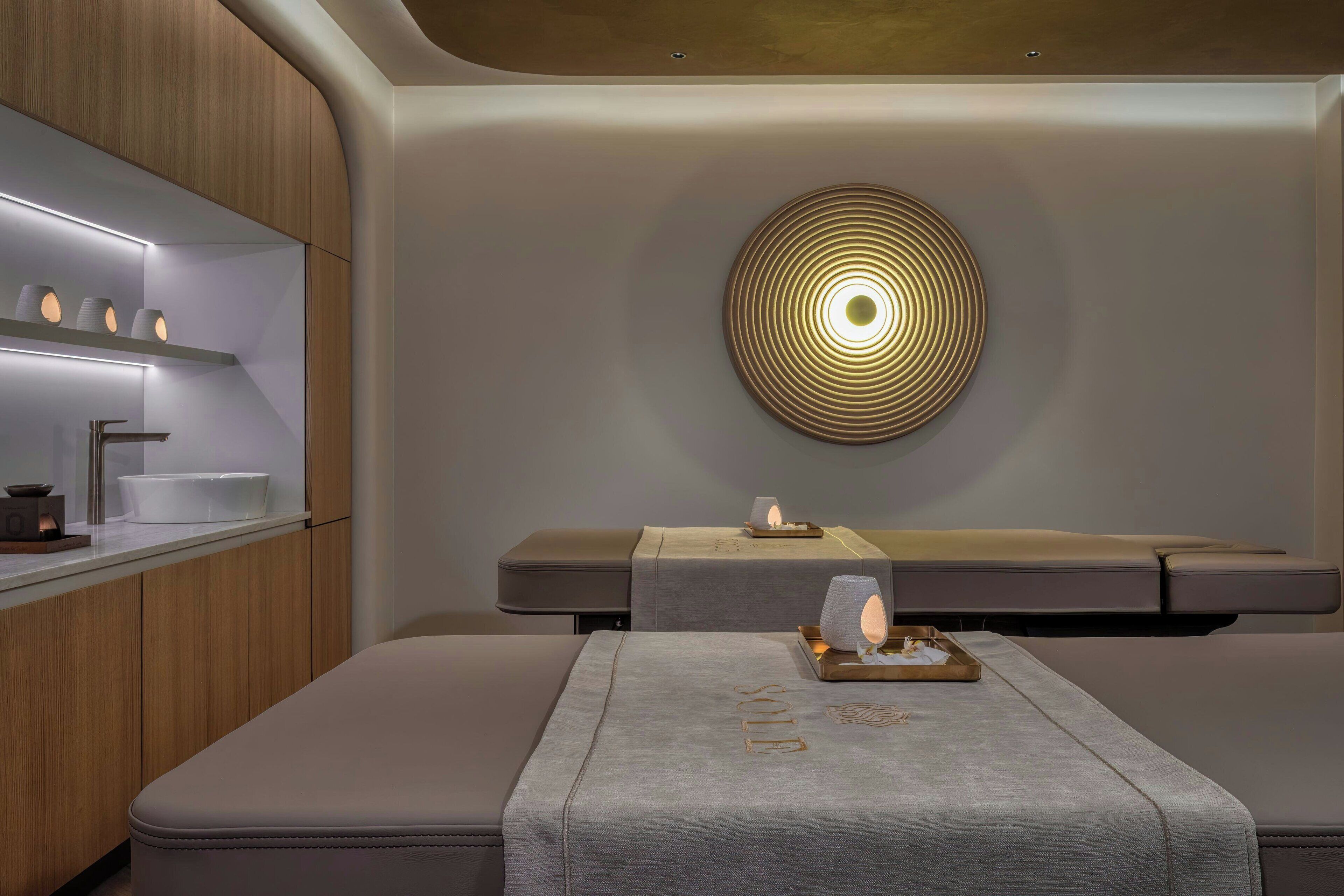 A modern, minimalist room with a built-in bench, a wall-mounted circular light fixture, and a shelf with a few items.