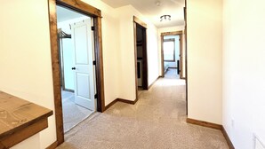 Un corridoio con pavimenti in moquette, finiture in legno e una porta che dà su un'altra stanza.