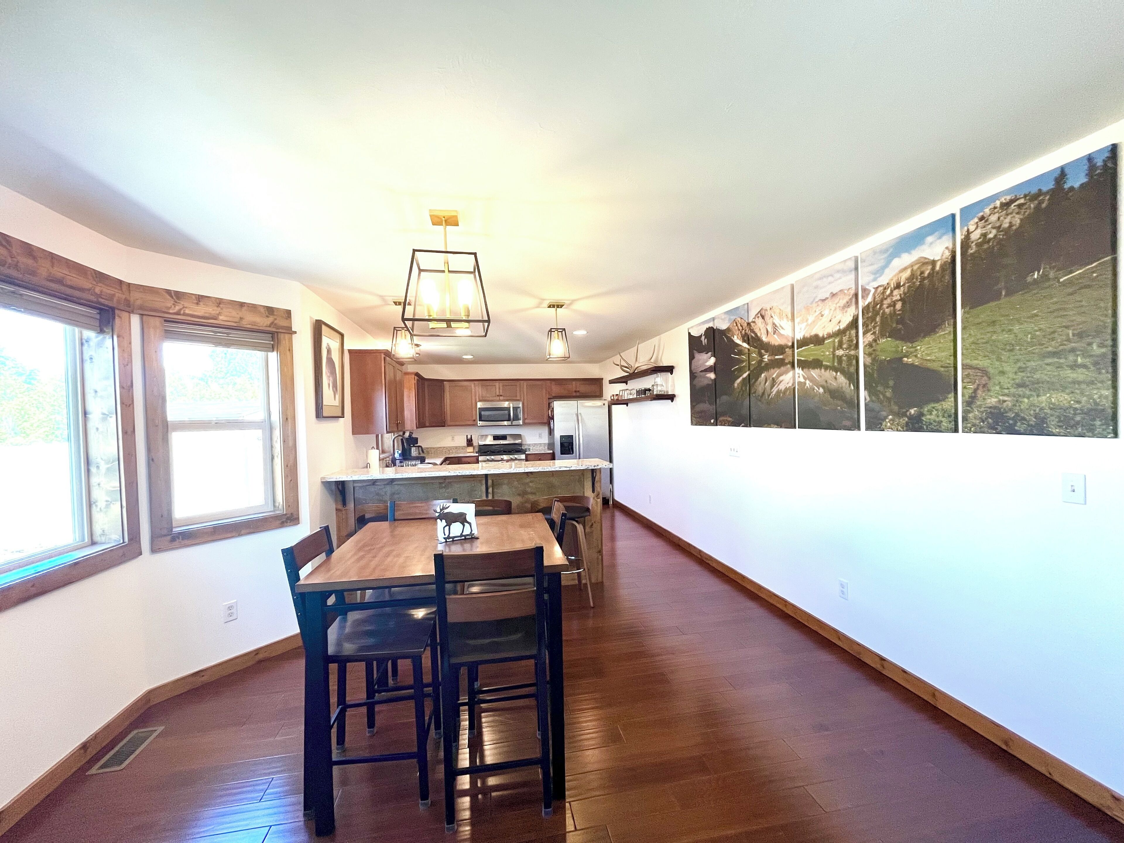 A modern kitchen with wooden cabinets, a central island, and a dining area with a wooden table and chairs.